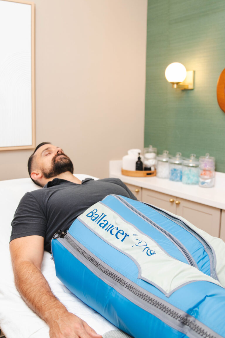man with eyes closed laying in a white bed doing Lymphatic Drainage theraphy